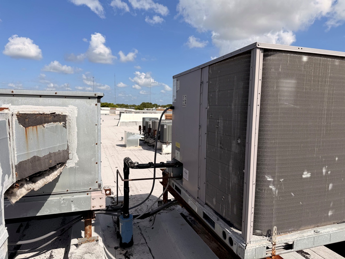 Large commercial rooftop HVAC equipment under a blue Miami sky